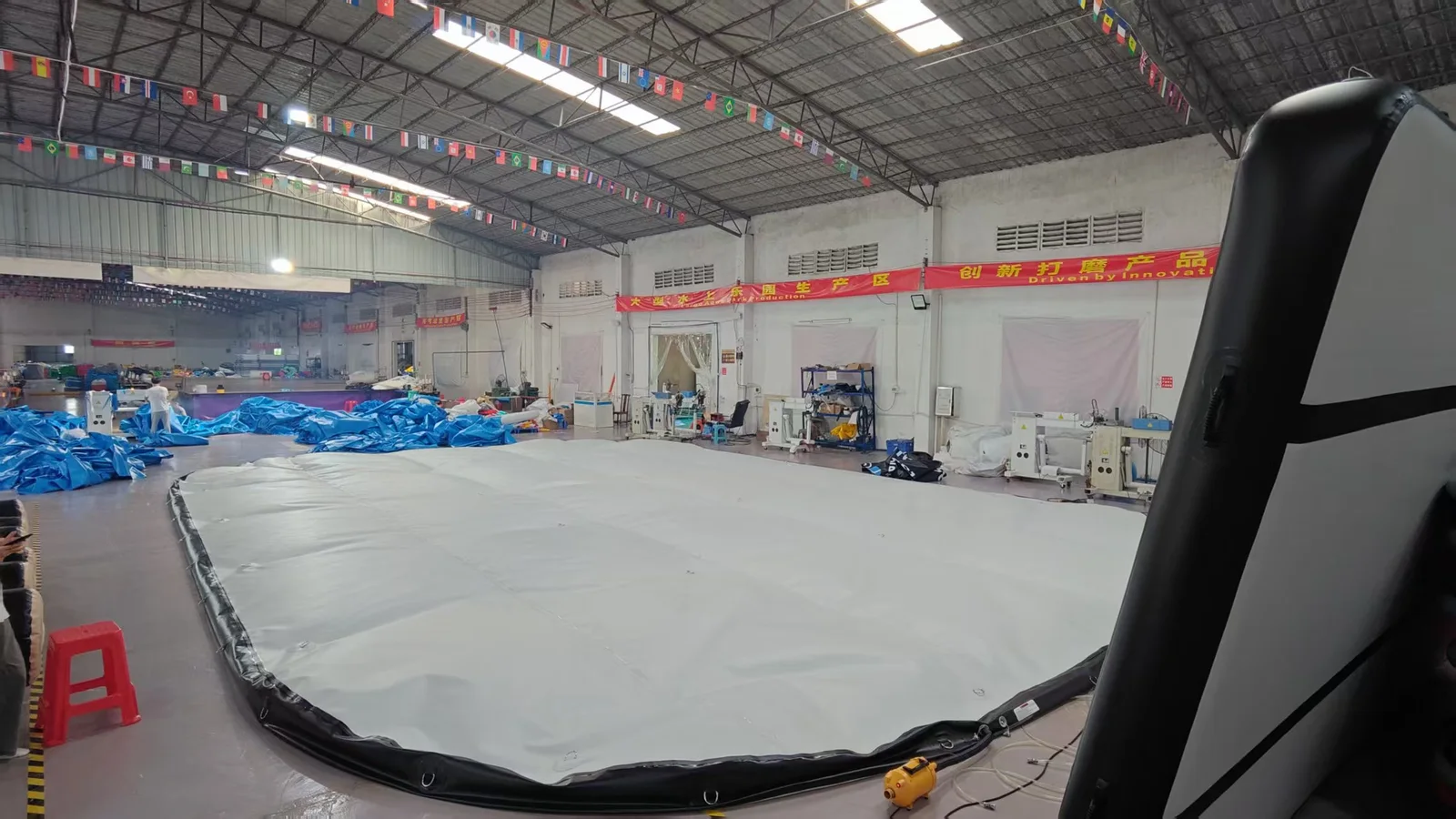 Large grey inflatable workpiece on the workshop floor beside production machines