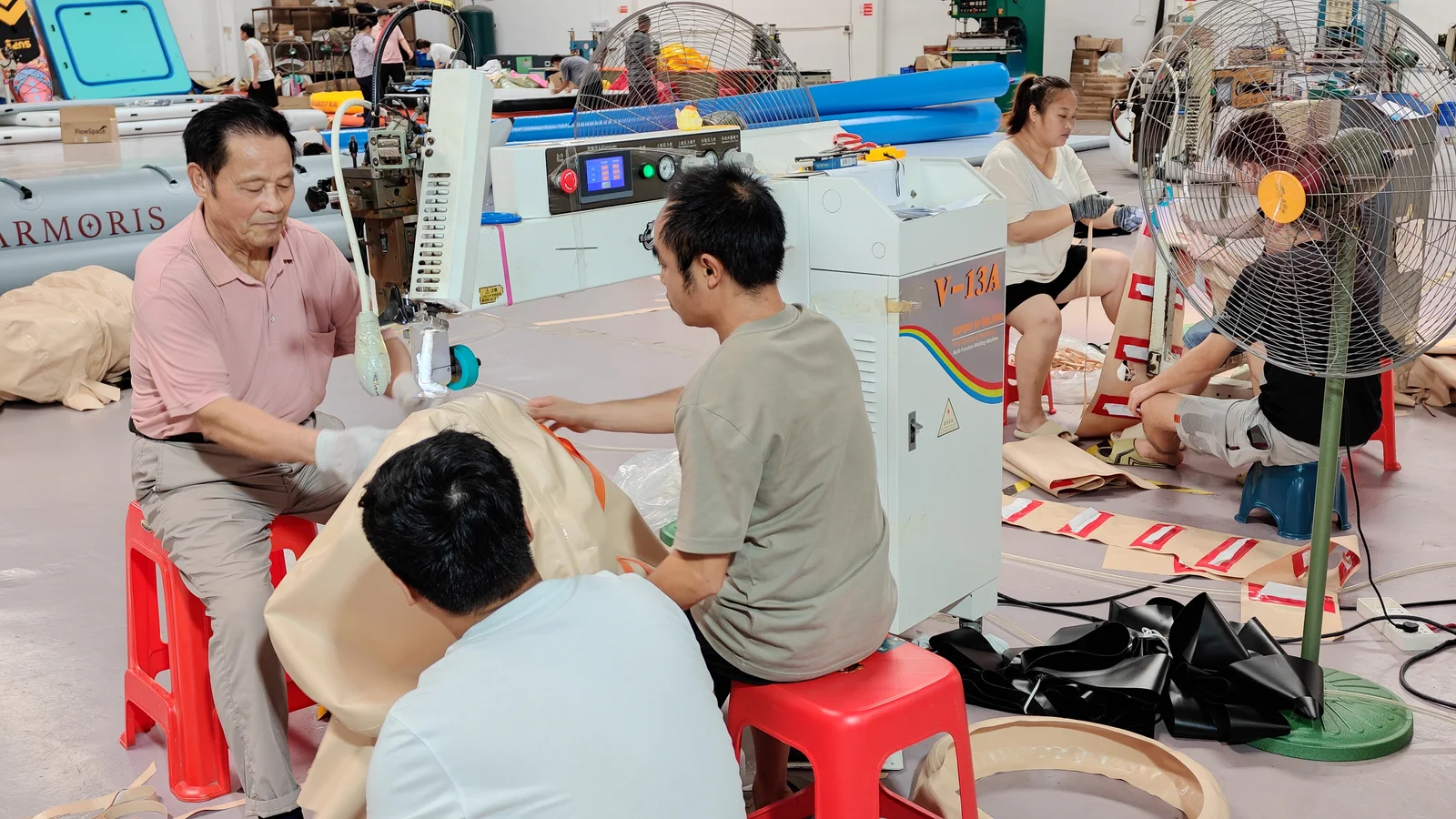 Team members handling inflatable material at a workshop machine